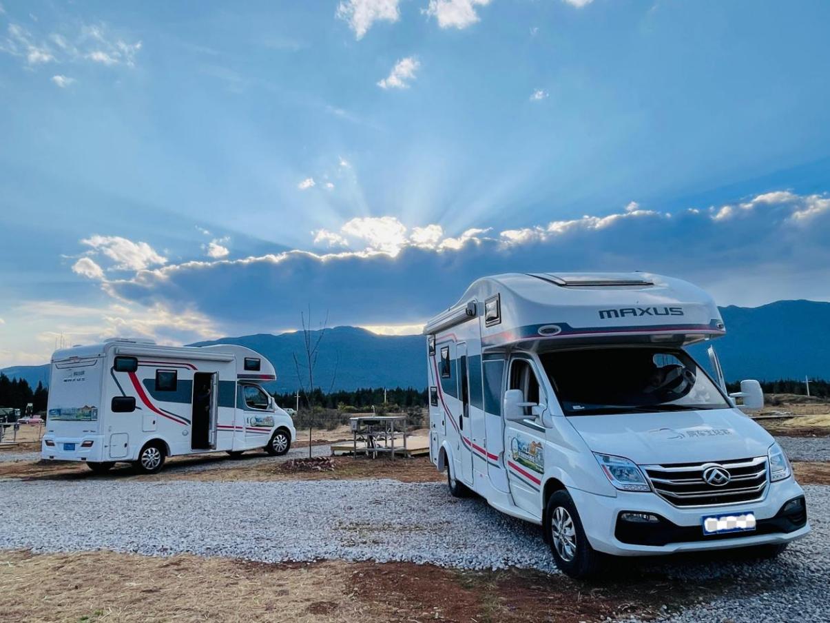 房車營地場景，兩輛房車停放在營地準備使用水電樁供電